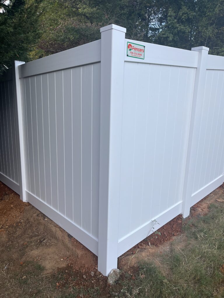 Fence specialist measuring post spacing and gate alignment with professional installation tools