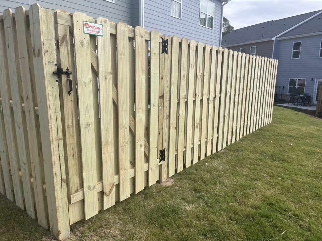 Fence installer setting posts precisely with level and auger on graded residential lot