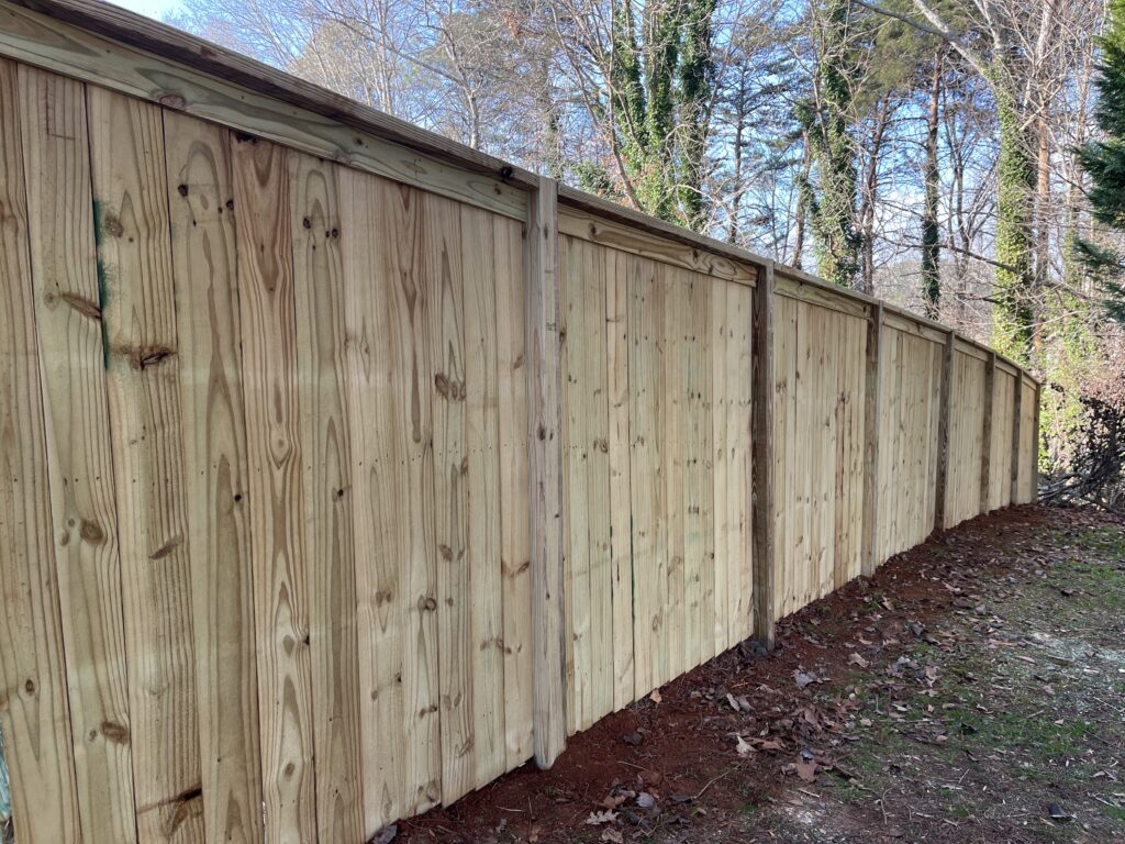 Crew installing privacy fence along sloped Lawrenceville backyard for safer pet containment