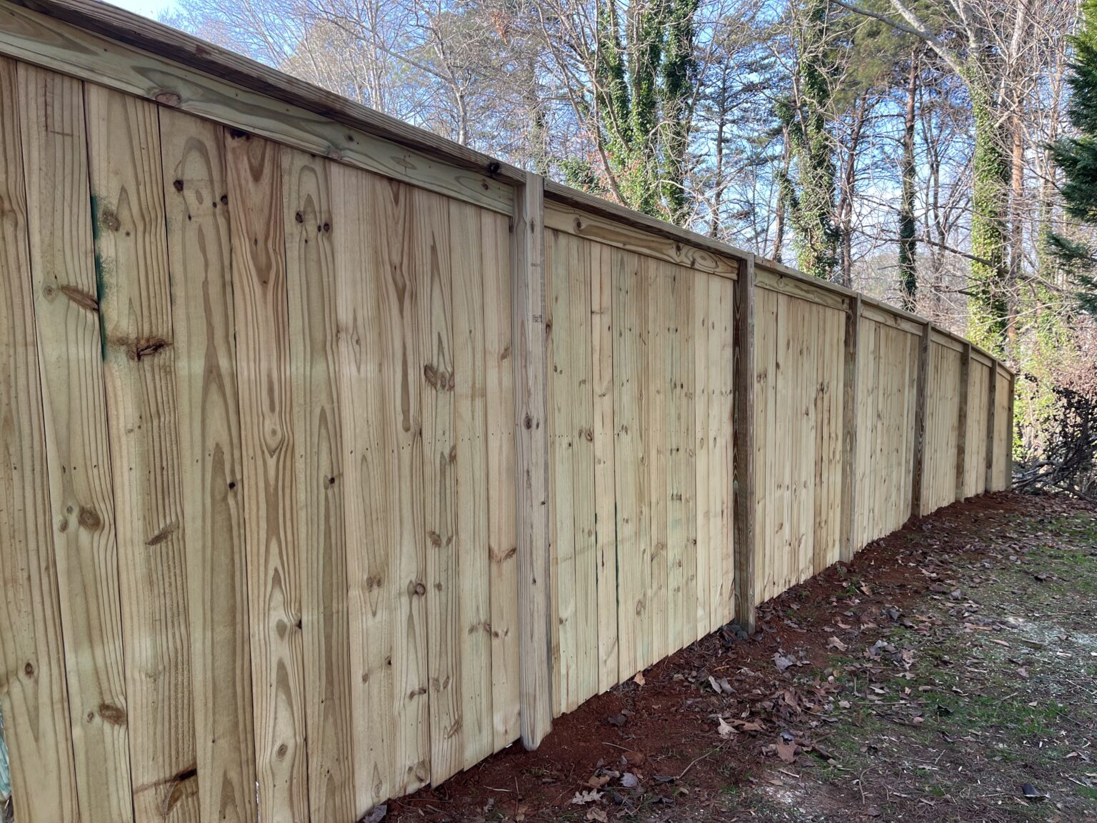 Crew installing privacy fence along sloped Lawrenceville backyard for safer pet containment