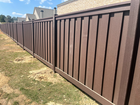 Advanced Trex Fence in Athens, GA installed for residential privacy and modern curb appeal, Experienced fence professional measuring grade and checking post alignment on uneven ground