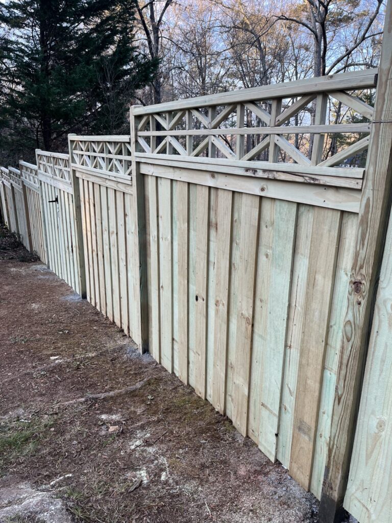 Fence installers aligning privacy panels beside a suburban patio and lawn