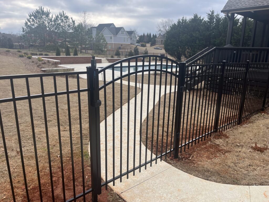 Skilled fencing contractor measuring gate spacing beside a backyard fence in Winterville - GA