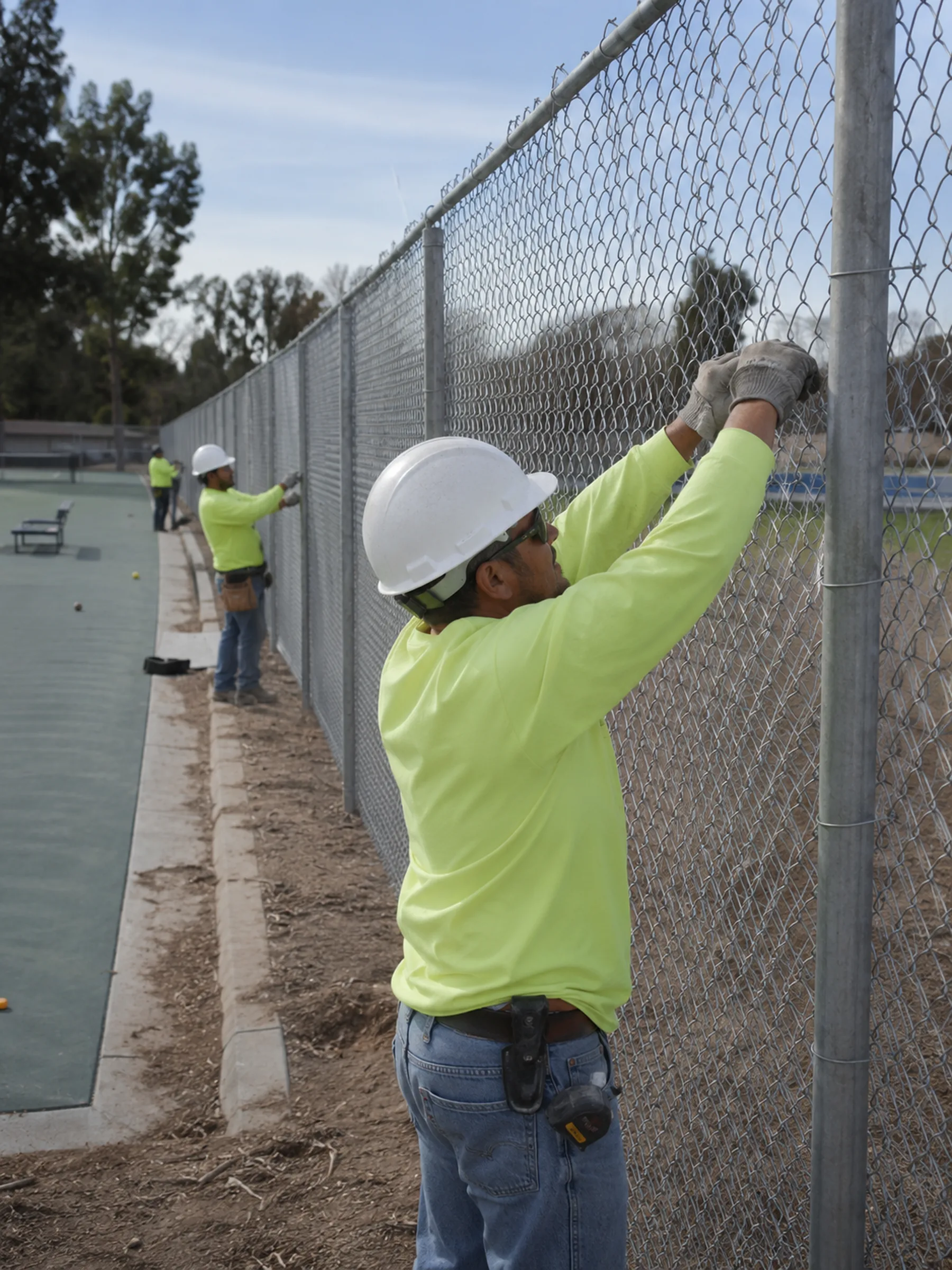 Chain Link Fence Installation in Winterville - GA underway as a crew stretches fencing along a backyard line